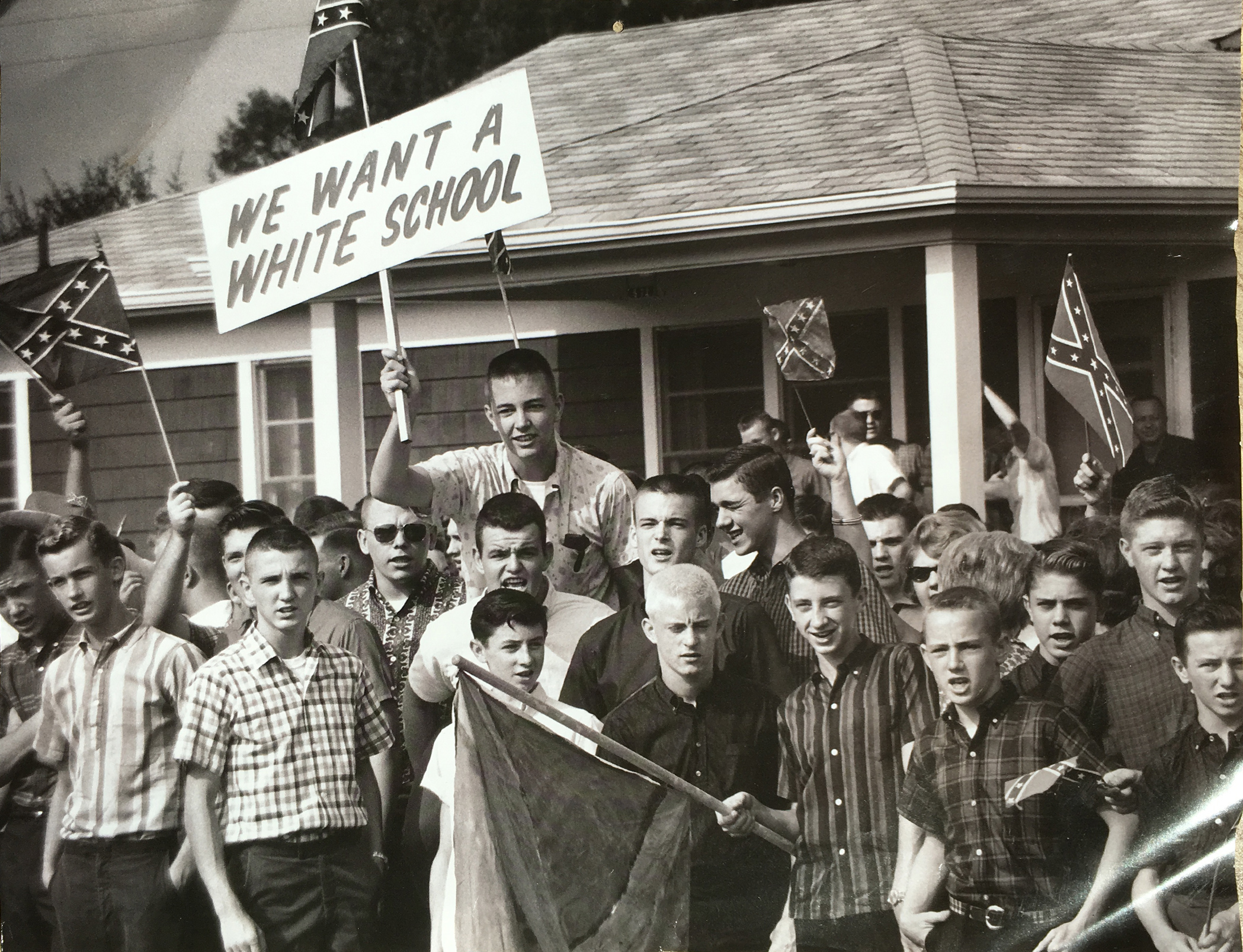 White boys waving racist signs and flags in front of a house