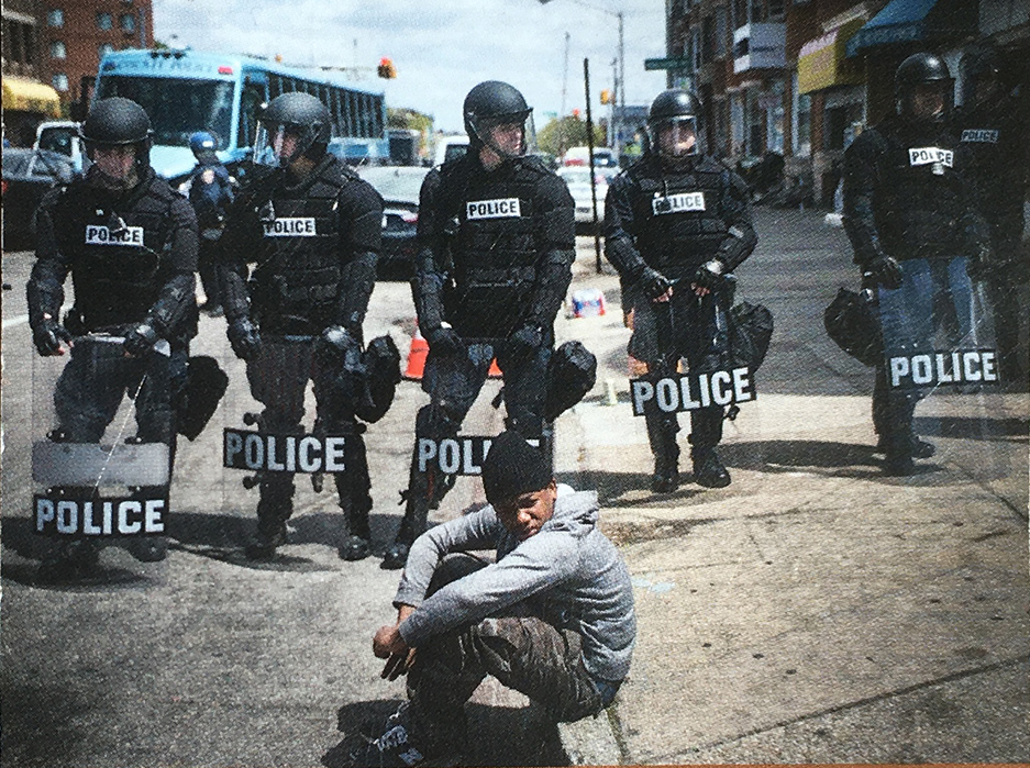 Police line in street, black boy sitting on curb